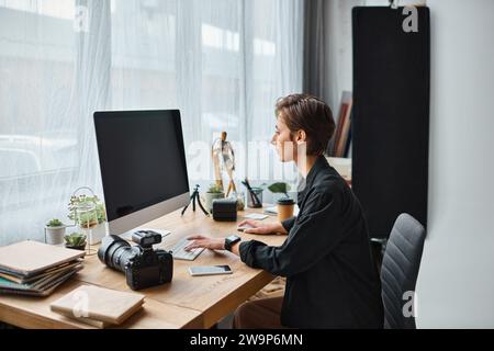 charming professional female photographer in casual wear retouching photos on computer at her studio Stock Photo