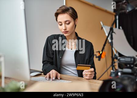 charming young female photographer in casual comfy attire paying online with her credit card Stock Photo