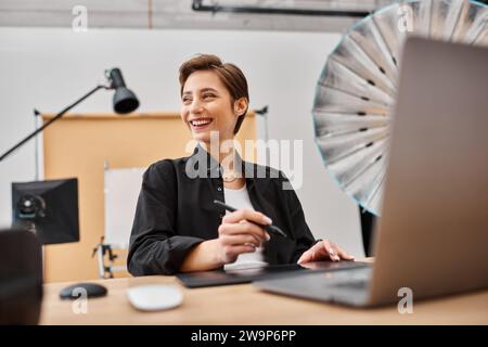 joyful professional female designer in casual attire working with her drawing tablet in studio Stock Photo