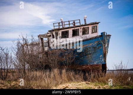 Abandoned wooden fishing boat slowly rotting away on the Eastern Shore of Nova Scotia, Canada. Stock Photo
