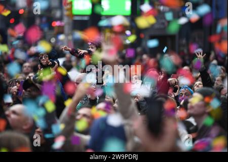 New York, USA. 29th Dec, 2023. People reach for floating confetti released during the 2024 Times Square New Year's Eve confetti test, New York, NY, December 29, 2023. (Photo by Anthony Behar/Sipa USA) Credit: Sipa USA/Alamy Live News Stock Photo