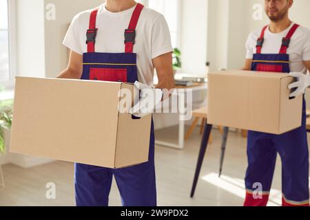 Two workers from a commercial moving service are carrying packed up cardboard boxes Stock Photo
