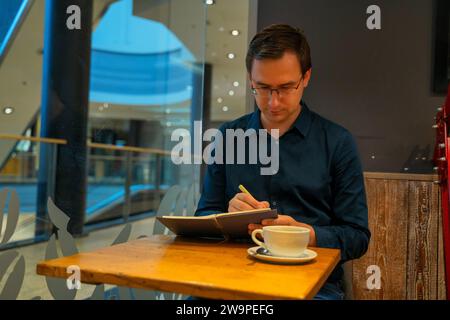 Thoughtful mature adult business man writing in notebook, middle aged author or writer taking notes thinking of new ideas, mature male student making Stock Photo