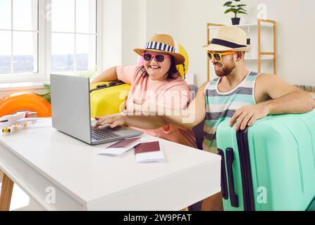 Funny couple planning vacation trip while sitting at home with packed suitcases Stock Photo