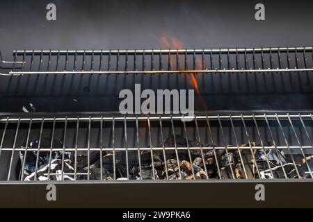 Barbecue grill pit with glowing and flaming hot open fire with red flame, hot charcoal briquettes and embers Stock Photo