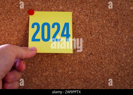 a man's hand pulling out a sticky note. year change from 2023 to 2024. 2024 year consept idea. Stock Photo