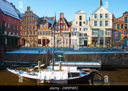 Colourful house facades, gabled houses, old harbour on the street Am Stintmarkt, in the water two snow-covered historic sailing boats or sailing Stock Photo