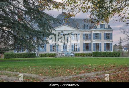 Large french house with a small car parked outside and blue painted shutters Stock Photo