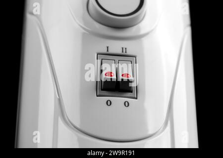 Home electric oil heater with control panel close up. Domestic heating radiator with switches and adjustable knob Stock Photo