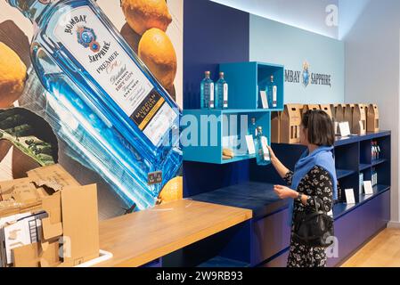 A woman browsing speciality Bombay Sapphire gin bottles and gift sets at the Bombay Sapphire distillery shop at Laverstoke Mill, Whitchurch, England Stock Photo