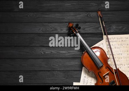 Violin, bow and music sheets on black wooden table, top view. Space for text Stock Photo