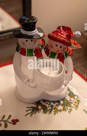 Colorful table top Christmas ornament depicting a snow man and woman holding a candle Stock Photo