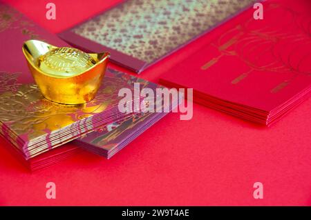Red envelope and golden ingots on red cover background with Chinese New Year wishes. Stock Photo