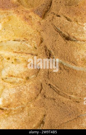 Vertical overhead close-up of a fresh apple pie, split into two halves. One half is dusted with aromatic cinnamon, the other remains pure and unadorne Stock Photo