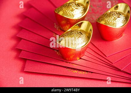 Red envelope and golden ingots on red cover background with Chinese New Year wishes. Stock Photo