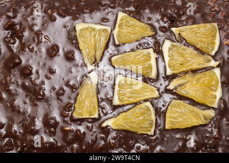 Top view of orange segments arranged in triangular shapes on the chocolate and almond texture of a cocoa cake. Texture and flavors. Stock Photo