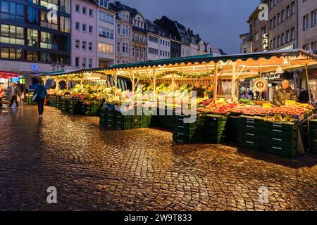 Bonn, Germany - December 23, 2023 : View of an outdoor market selling fresh fruit and vegetables in the market square of Bonn Germany at dusk Stock Photo