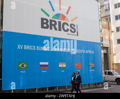 (231230) -- BEIJING, Dec. 30, 2023 (Xinhua) -- People walk near the Sandton Convention Center, the venue of the 15th BRICS Summit in Johannesburg, South Africa, Aug. 21, 2023. Top 10 world news events in 2023 5. The Global South's resounding support for multilateralism On Aug. 24, the BRICS cooperation mechanism witnessed a historic expansion as countries including Saudi Arabia, Egypt, the UAE, Iran and Ethiopia were invited to join the BRICS family. On Sept. 9, the African Union was invited to officially become a member of the G20. Currently, the strength of developing countries is c Stock Photo