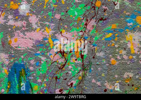 White plastered wall splattered with red paint. Paint splashes on the wall. Painted plaster wall. Abstract background. Painted plaster texture. Stock Photo