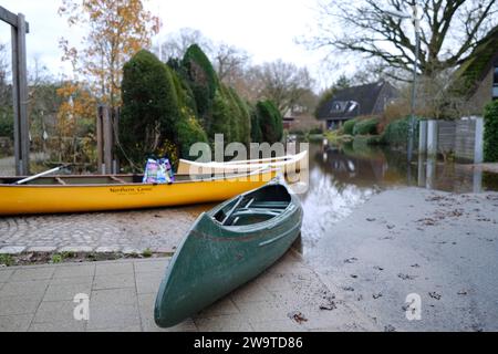 Borgfeld, Germany. 30th Dec, 2023. Canoes stand on a flooded street in Borgfeld near Bremen. The River Wümme has burst its banks here. Residents can only reach their homes by boat. Credit: Markus Hibbeler/dpa/Alamy Live News Stock Photo