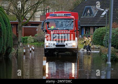 Borgfeld, Germany. 30th Dec, 2023. A fire department emergency vehicle drives through a flooded street in Borgfeld near Bremen. The river Wümme has burst its banks here. Credit: Markus Hibbeler/dpa/Alamy Live News Stock Photo