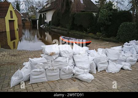 Borgfeld, Germany. 30th Dec, 2023. Sandbags lie ready in Borgfeld near Bremen. The river Wümme has burst its banks here. Credit: Markus Hibbeler/dpa/Alamy Live News Stock Photo