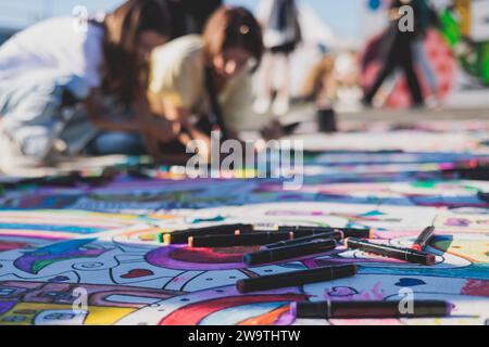 Process of drawing on asphalt and pavement, kids and children with crayons, chalk and markers, teens creating street art on the ground, graffiti and p Stock Photo