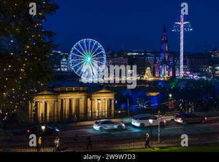 Big ferris wheel and star flyer fairground rides lit up at night at Christmas market Edinburgh, Scotland, UK Stock Photo