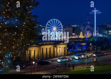 Big ferris wheel and star flyer fairground rides lit up at night at Christmas market Edinburgh, Scotland, UK Stock Photo