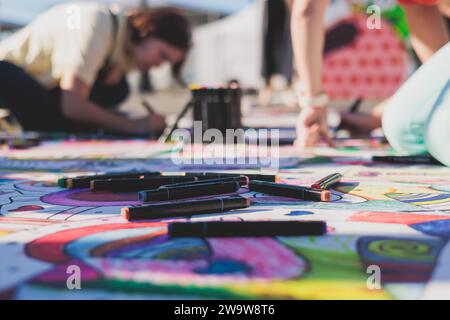 Process of drawing on asphalt and pavement, kids and children with crayons, chalk and markers, teens creating street art on the ground, graffiti and p Stock Photo