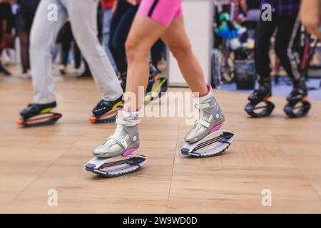 Fit legs in kangoo jumping shoes. Three sexy girls do sport kangoo  exercises on pink background . Group fitness. Stock Photo