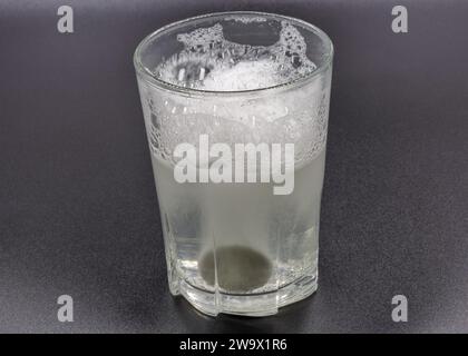 Dissolving instant effervescent tablets in a glass of water closeup on black Stock Photo