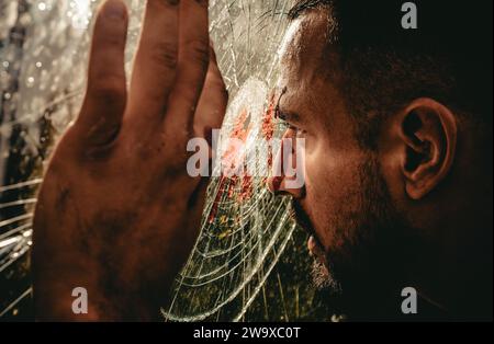 Victim of war. Wounded man victim looking through broken glass. Crime or violence victim. Victim of accident Stock Photo