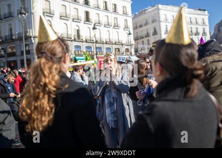 A group of friends celebrate the arrival of a new year in the Puerta del Sol square. Like every December 30, hundreds of people have celebrated the beginning of the new year in advance. As a tradition, in Madrid families and friends have celebrated by drinking New Year's grapes. Stock Photo