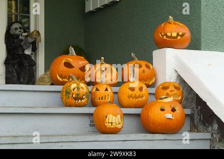 Humorous carved Halloween pumpkins displayed on the wooden front stairs of a house Stock Photo