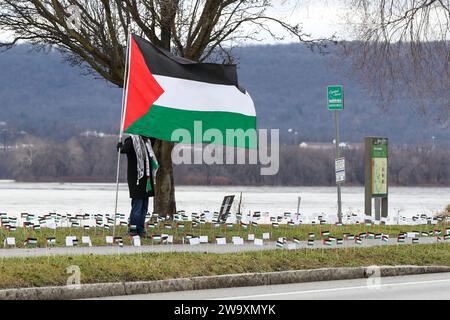 Harrisburg, United States. 30th Dec, 2023. A man holds a Palestinian flag on the bank of the Susquehanna River in Harrisburg Pa. on December 30, 2023. Demonstrators placed more than 20,000 flags, one for each person killed in Gaza since the beginning of the Israel-Hamas War, along the street near the Pennsylvania Governor's Residence. (Photo by Paul Weaver/Sipa USA) Credit: Sipa USA/Alamy Live News Stock Photo