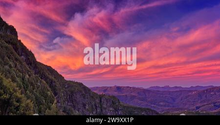Pink and red lit clouds at sunset over the West Coast Range from Lake Tahune, Franklin-Gordon Wild Rivers National Park, Tasmania, Australia Stock Photo