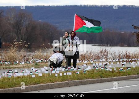 Harrisburg, United States. 30th Dec, 2023. Protesters hold flags as they walk along the Susquehanna River during a pro-Palestine rally. Demonstrators placed more than 20,000 flags, one for each person killed in Gaza since the beginning of the Israel-Hamas War, along the street near the Pennsylvania Governor's Residence. Credit: SOPA Images Limited/Alamy Live News Stock Photo