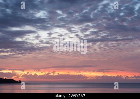 Stunningly vibrant and colourful pastel cloudy sunset over the ocean, taken in South Australia. Showing just a small amount of land. Stock Photo