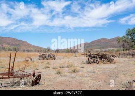 Deteriorating wooden carts and farm machinery in an arid paddock during a very dry season. Backed by the mountains of the Flinders Ranges in South Aus Stock Photo