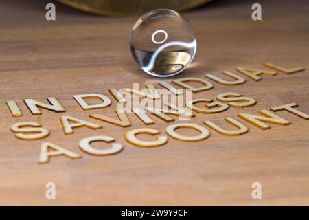 ISA, Individual Savings Account in wooden letters on a wooden surface  with a glass crystal ball. future of savings Stock Photo