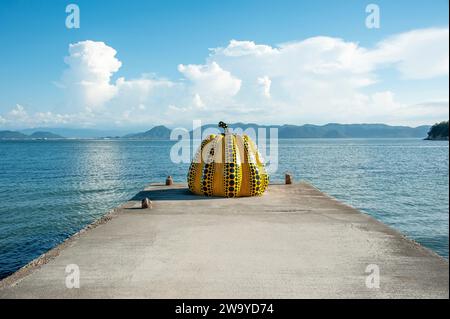 The famous spotty yellow pumpkin artwork by Yayoi Kusama sits at the end of a pier on Naoshima, known as Japan's art island, in Kagawa Prefecture. Stock Photo