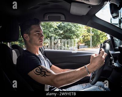 Handsome young man using mobile phone while driving a car Stock Photo