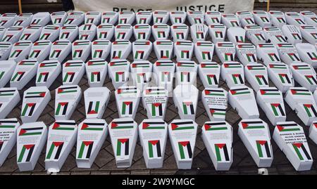 London, UK. 30th Dec, 2023. Cardboard “child coffins” with Palestinian flags, representing the children killed by Israeli airstrikes in Gaza, are seen during the demonstration. Pro-Palestine activists staged a demonstration outside the Science Museum in South Kensington, calling on the museum to drop its sponsor Adani Group, which has ties to Israeli weapons manufacturing. Credit: SOPA Images Limited/Alamy Live News Stock Photo