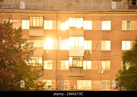 A building in the city is flooded with sunshine and a summer street with cars. Windows in the sun. Stock Photo