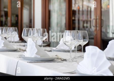 Large table elegantly set up for a special occasion such a wedding or a formal event, covered with white tablecloths, neatly folded linen napkins Stock Photo