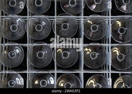 Upside-down wine glasses positioned in a plastic container with dividers forming a symmetrical pattern, abstract aesthetic and appealing composition Stock Photo