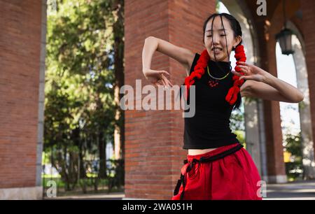 Portrait of funny asian woman moving her arms harmoniously in the street Stock Photo