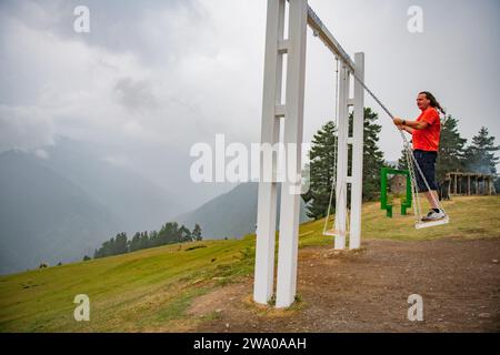 Skyward Soar: Man on Swing in Orange T-Shirt Stock Photo