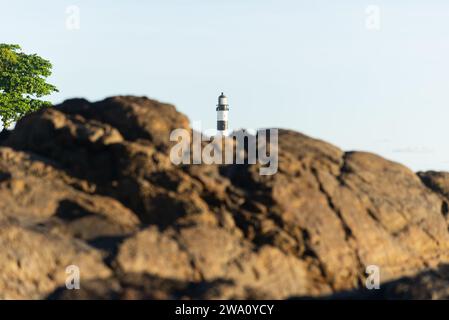 Salvador, Bahia, Brazil - October 21, 2023: View, between the rocks, of the Barra lighthouse tower in the city of Salvador, Bahia. Stock Photo